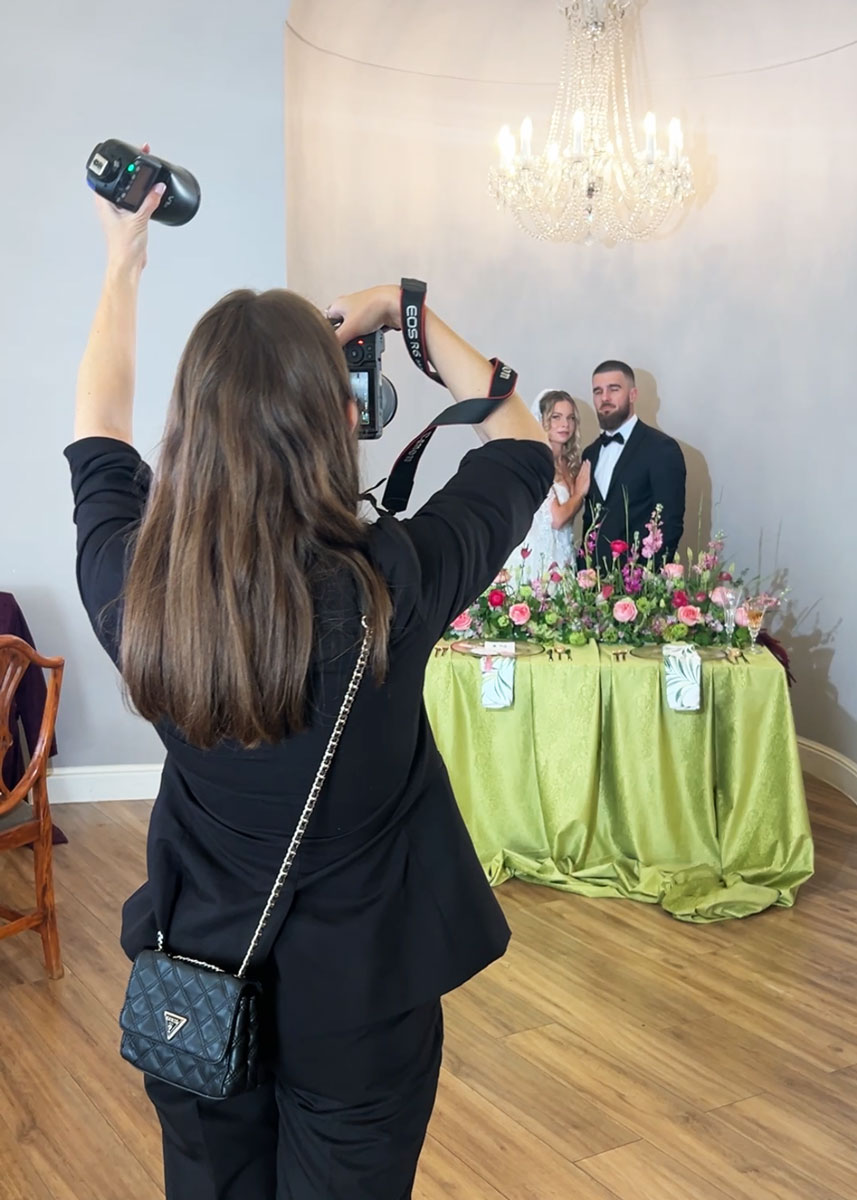 Svadobná fotografka fotografujúca mladomanželov s externým bleskom počas editorial svadobného fotenia